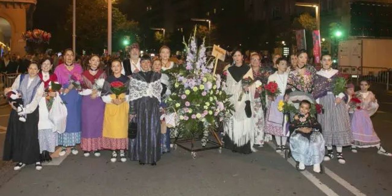 Grupo de participantes de Novaltia en la Ofrenda de Flores a la Virgen del Pilar con trajes tradicionales y ramos de flores.